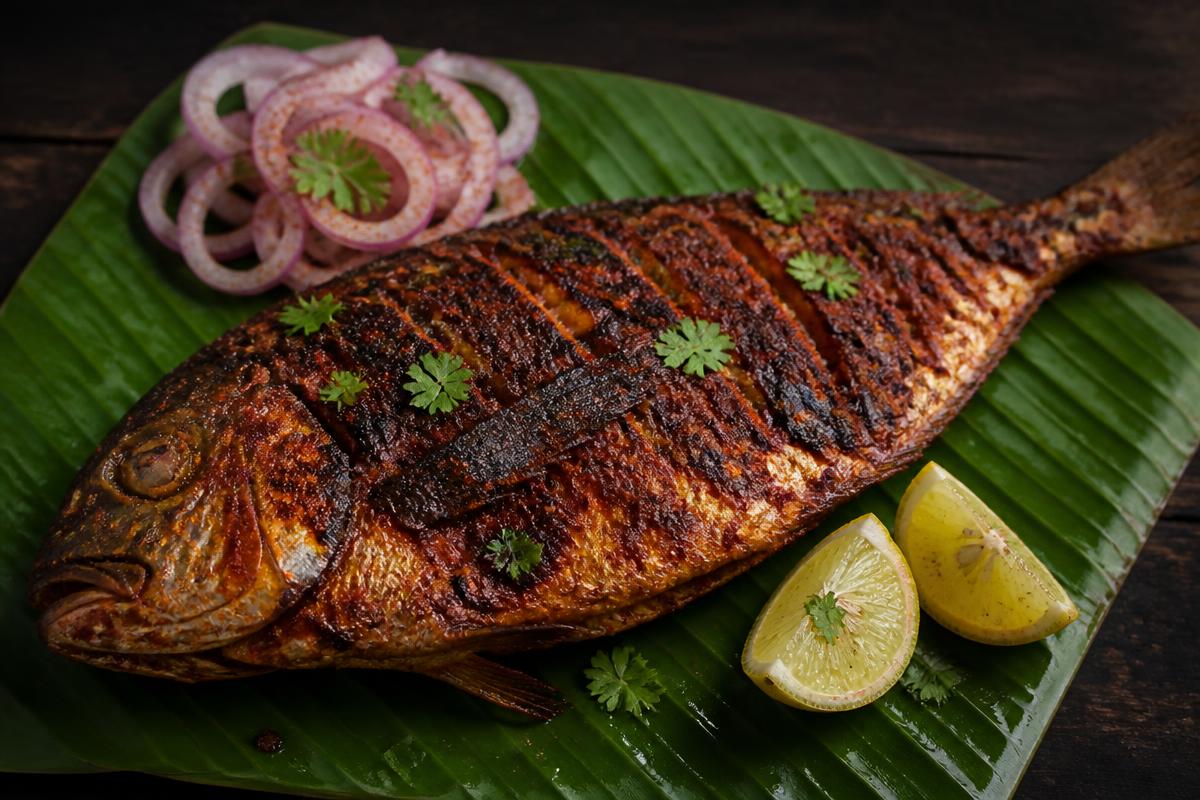 Whole grilled masala fish served on a banana leaf with lemon and onion